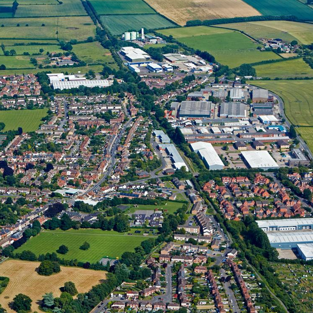 Aerial view of Thame, Oxfordshire, showing residential areas, commercial buildings, and surrounding countryside.